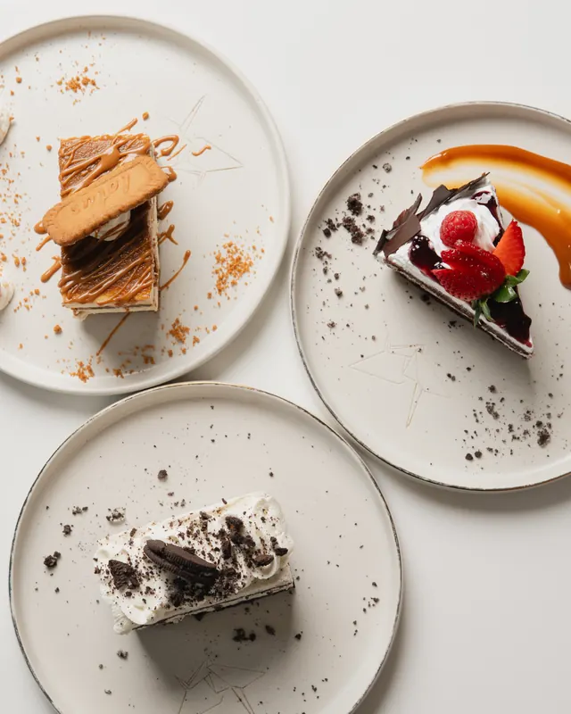 Three slices of cake on speckled plates, seen from above