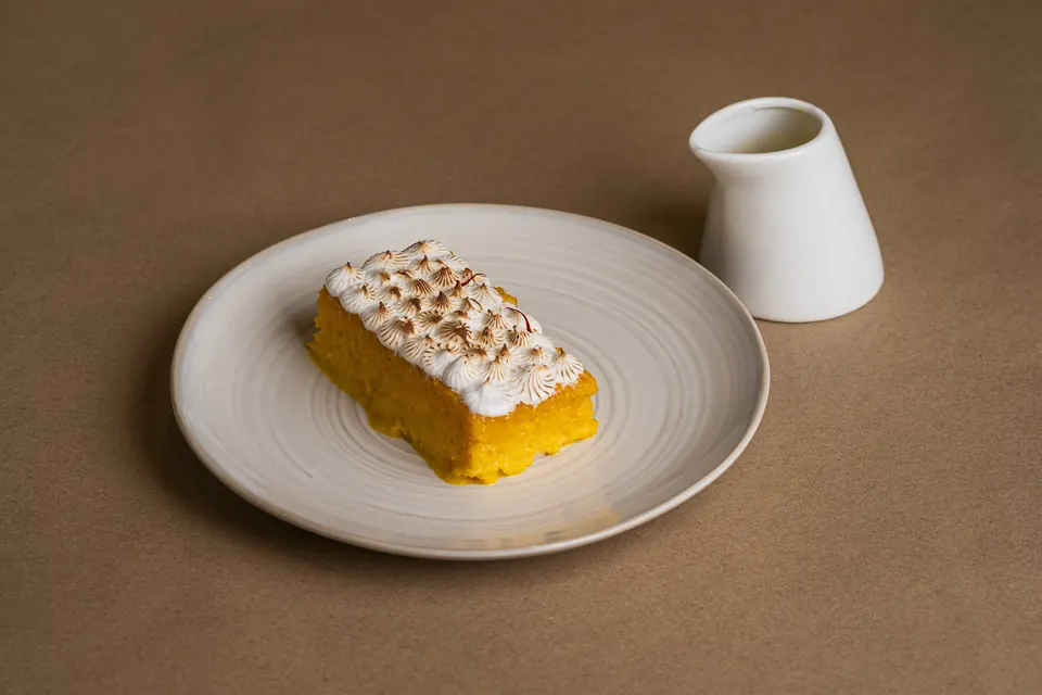 A torched meringue cake with a small milk jug