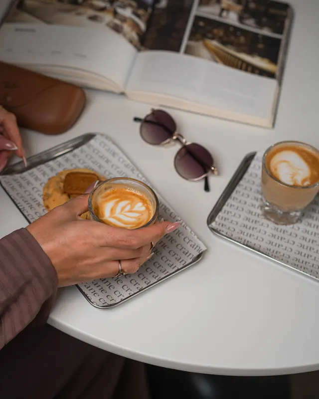 Latte art, a book and sunglasses on a café table