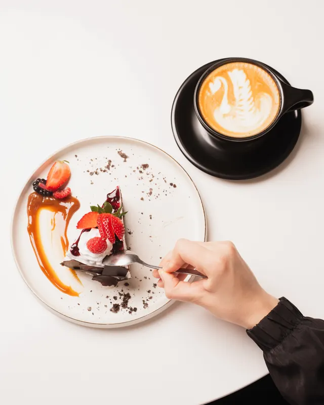 A latte with a swan poured in the foam, next to a chocolate dessert